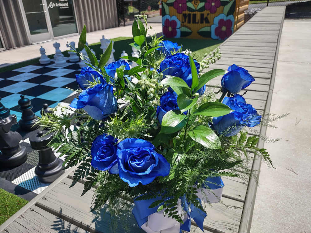 A dozen blue Roses, with assorted greenery and filler in a clear