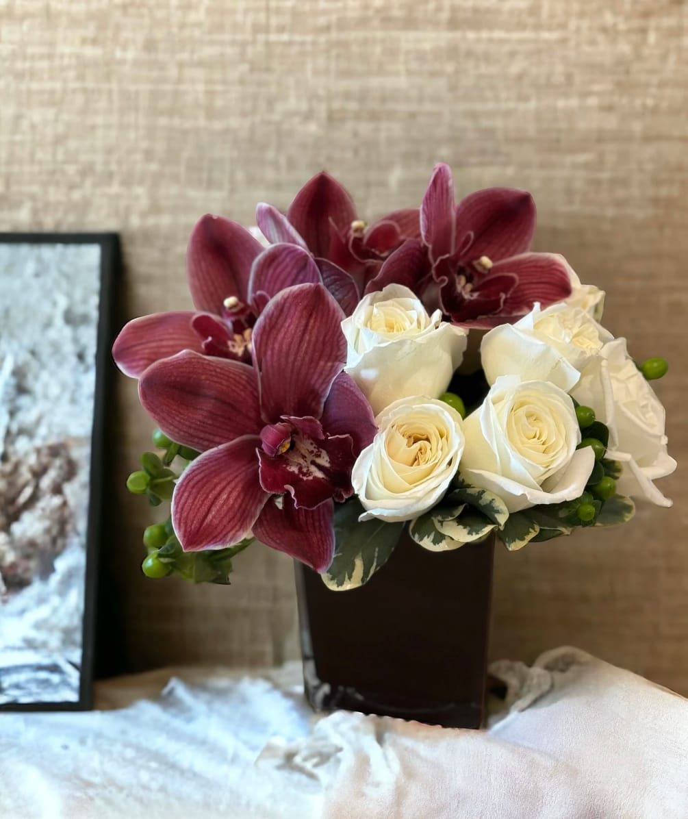 Burgundy cymbidium orchids and white roses which have been grouped by variety