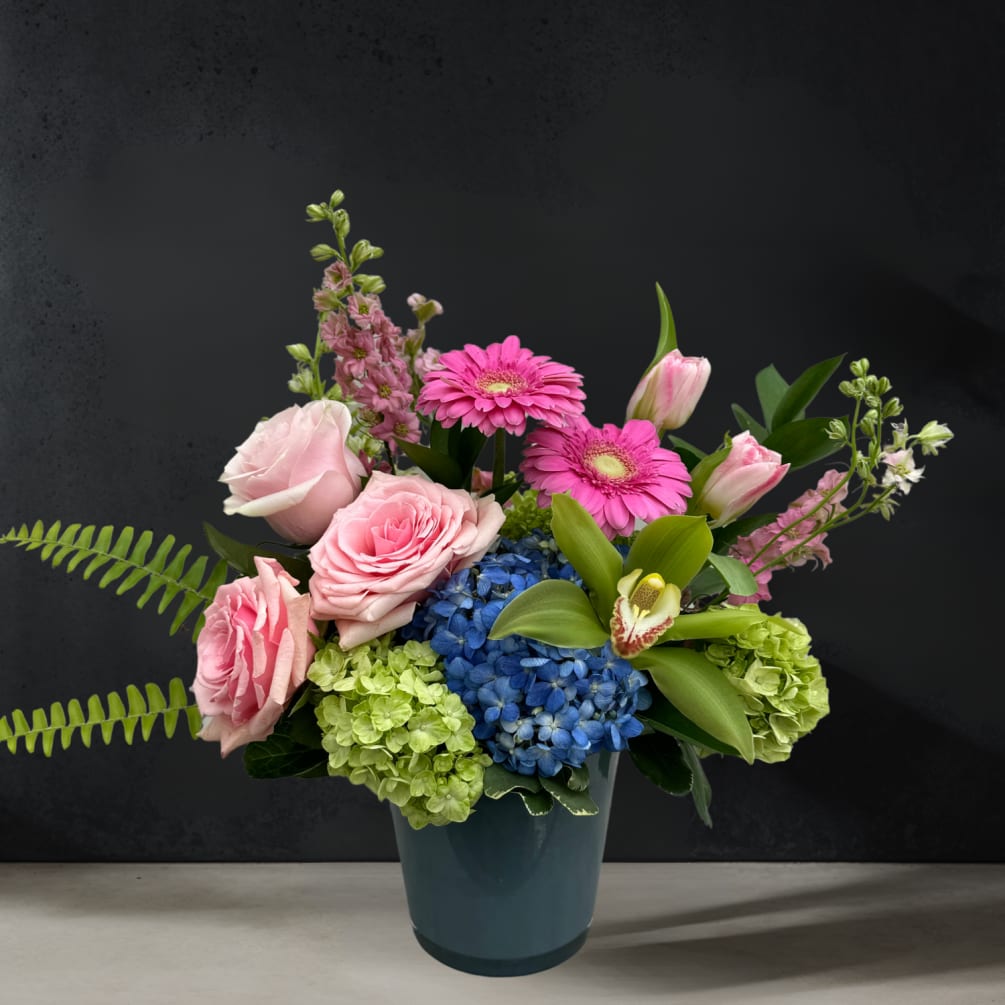 A chic gray glass vase holds a striking one-sided arrangement of blue