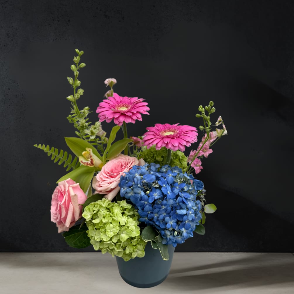 A chic gray glass vase holds a striking one-sided arrangement of blue