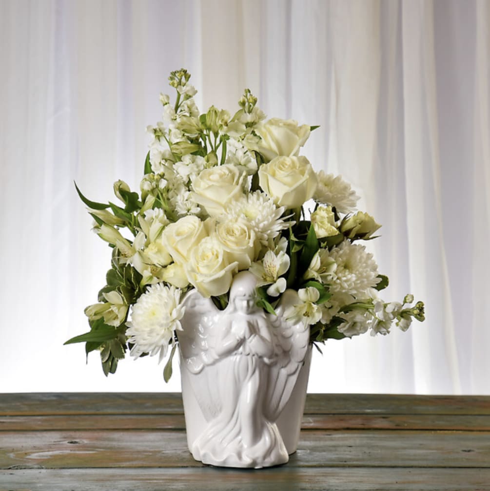 Presented in an elegant, ceramic angel vase, this assortment features white roses