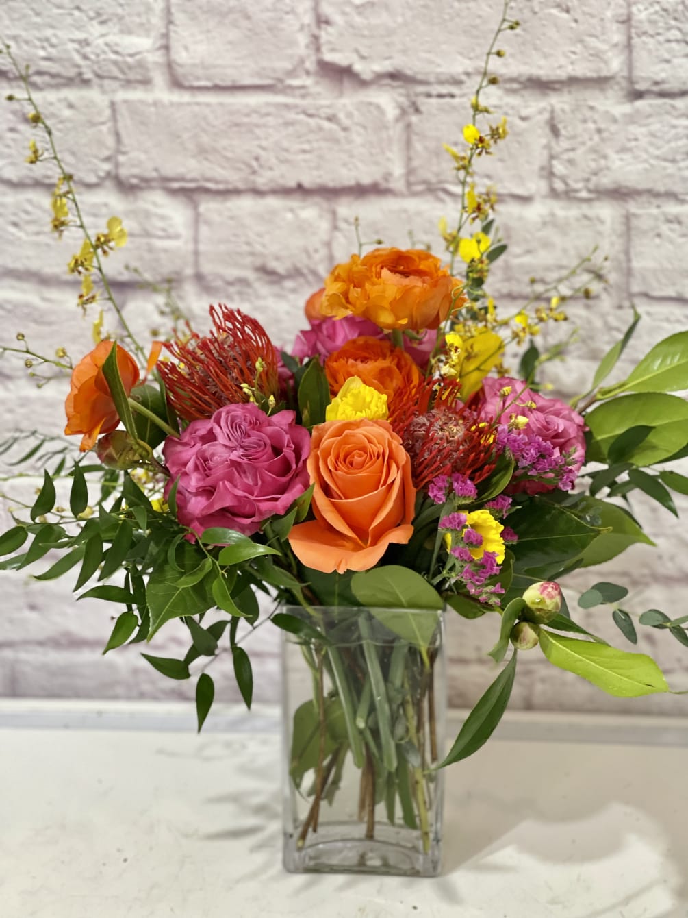 Orange Tiger lilies and orange roses in a glass vase. 