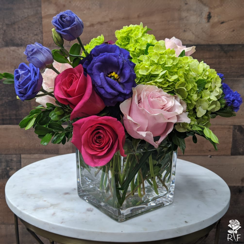 This arrangement includes hot pink roses, pink roses, green hydrangea, alstroemeria, lisianthus