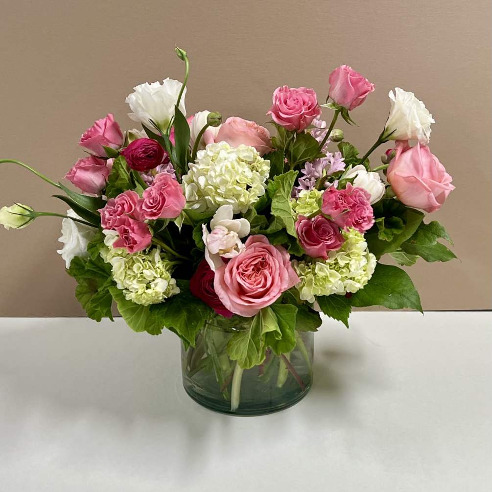 This arrangement has a mix of flowers including hydrangeas, roses, tulips, and