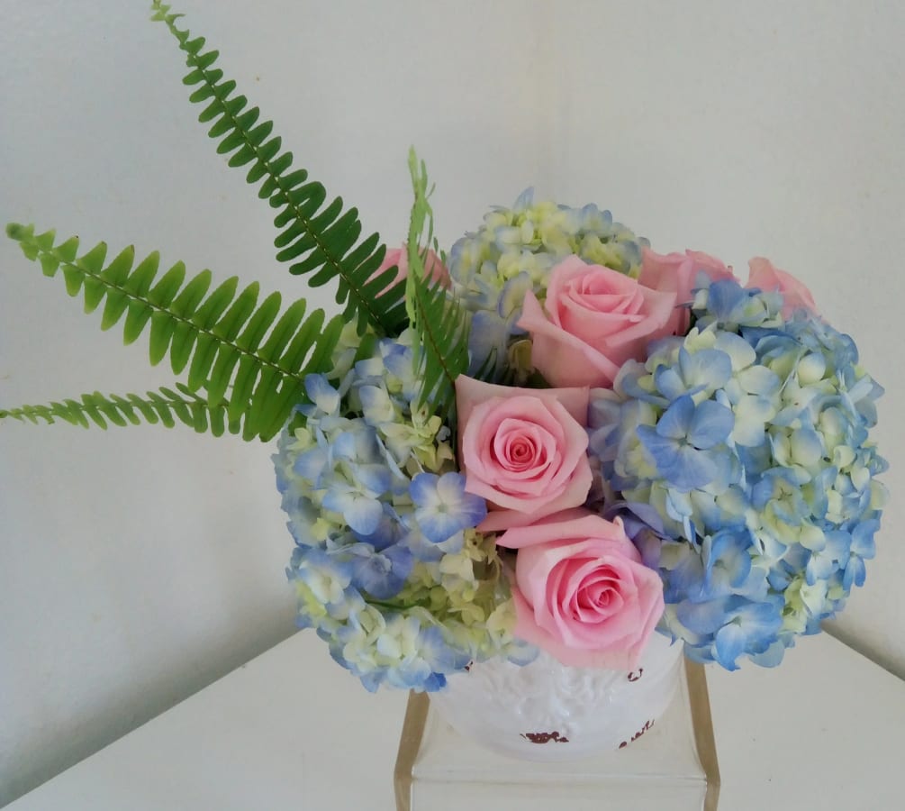 6 pink roses and hydrangea in a ceramic container