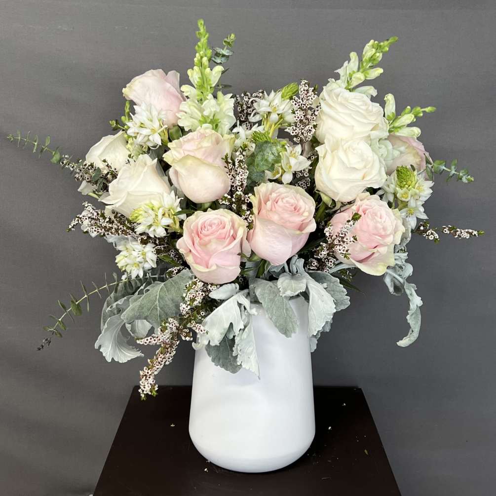 This floral arrangement is designed in a white ceramic vase. It has