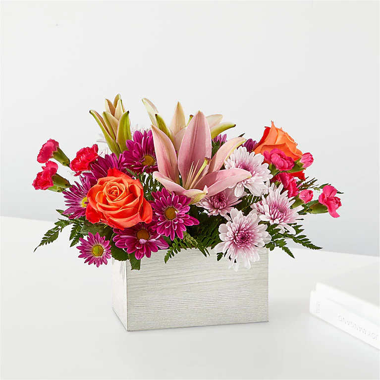 Hot pink carnations, orange roses, pink lilies, lavender cushion mums, and lush