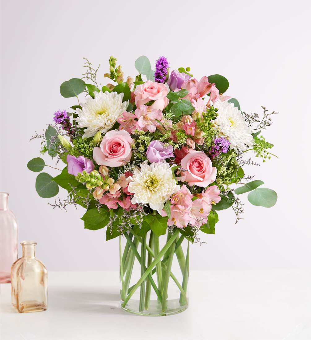 Clear glass vase filled with pink roses, lisianthus, pink spray roses, pink
