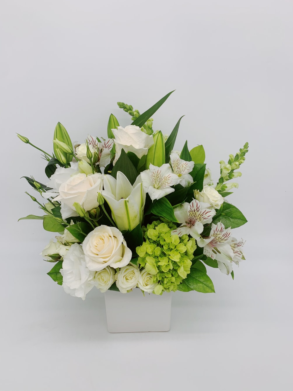 A mixed bouquet of green and white flowers to include white lilies