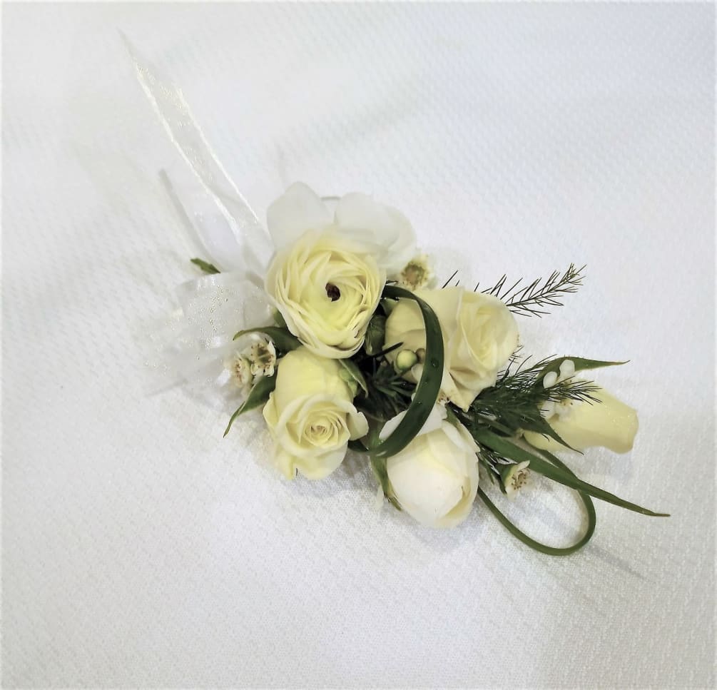 Wrist corsage with white ranunculus and spray roses accented with wax flower