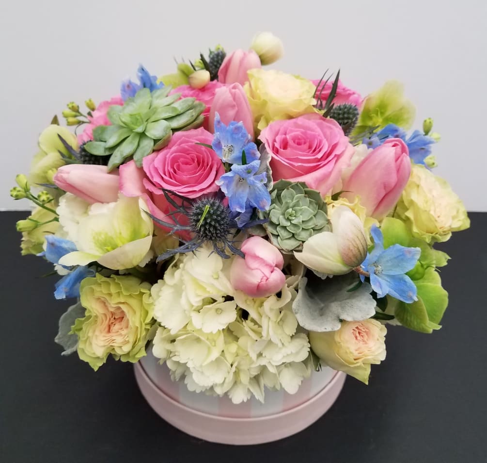 A pretty hat box filled with delicate blossoms in pastel colors including