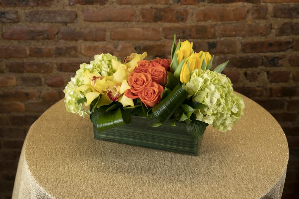 An exquisite display yellow and orange toned seasonal floral blooms designed in