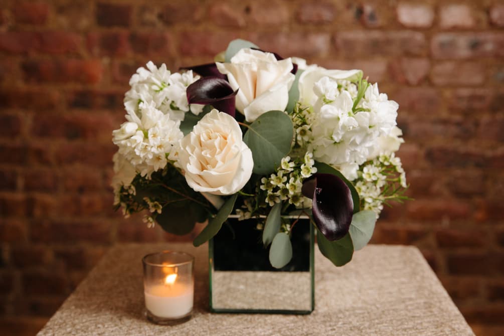 An elegant arrangement of white seasonal flowers with a deep touch displayed