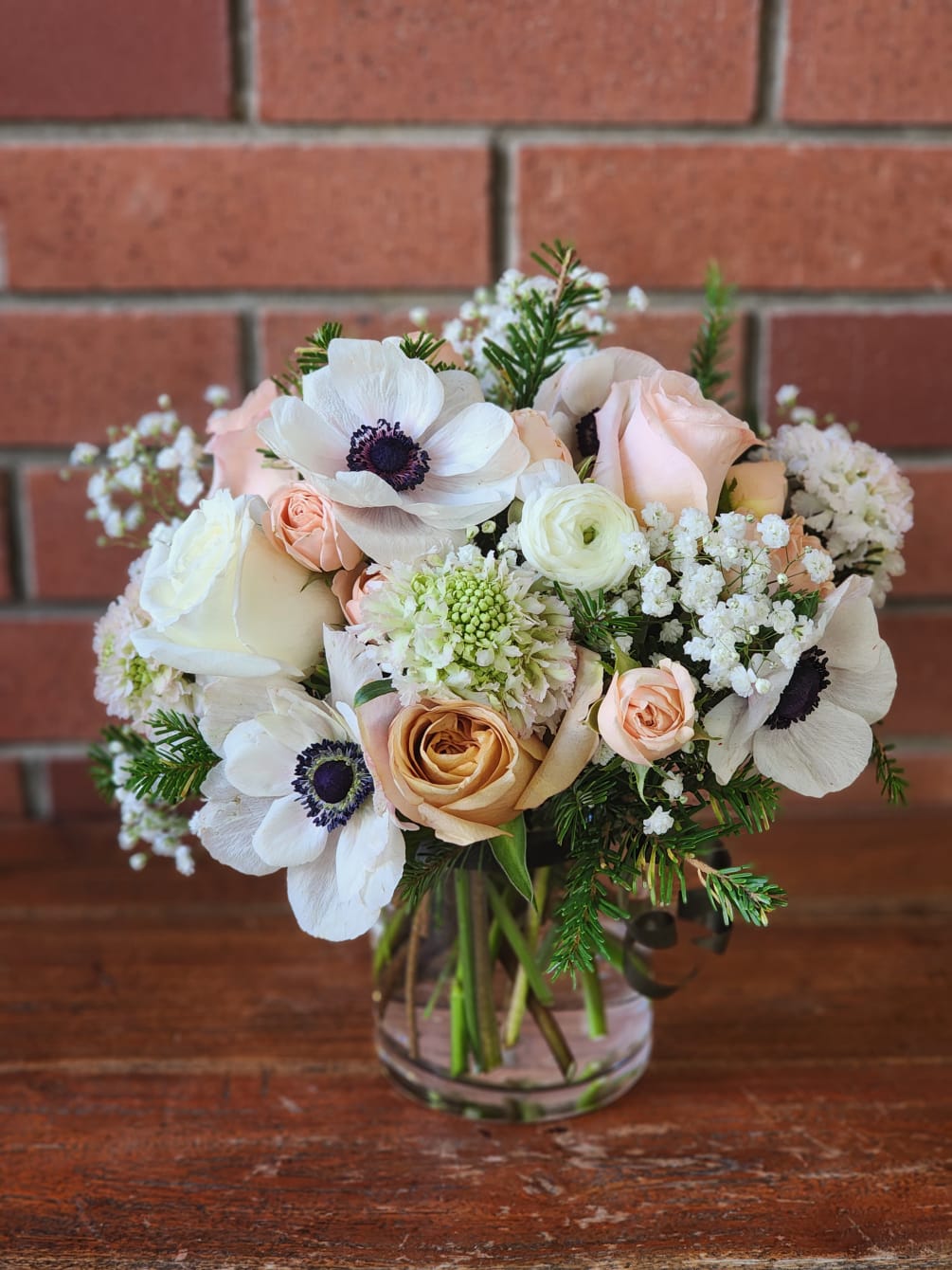 Modern rectangular vase filled with evergreens, blush antique roses, scabiosa, ranunculus, baby&#039;s