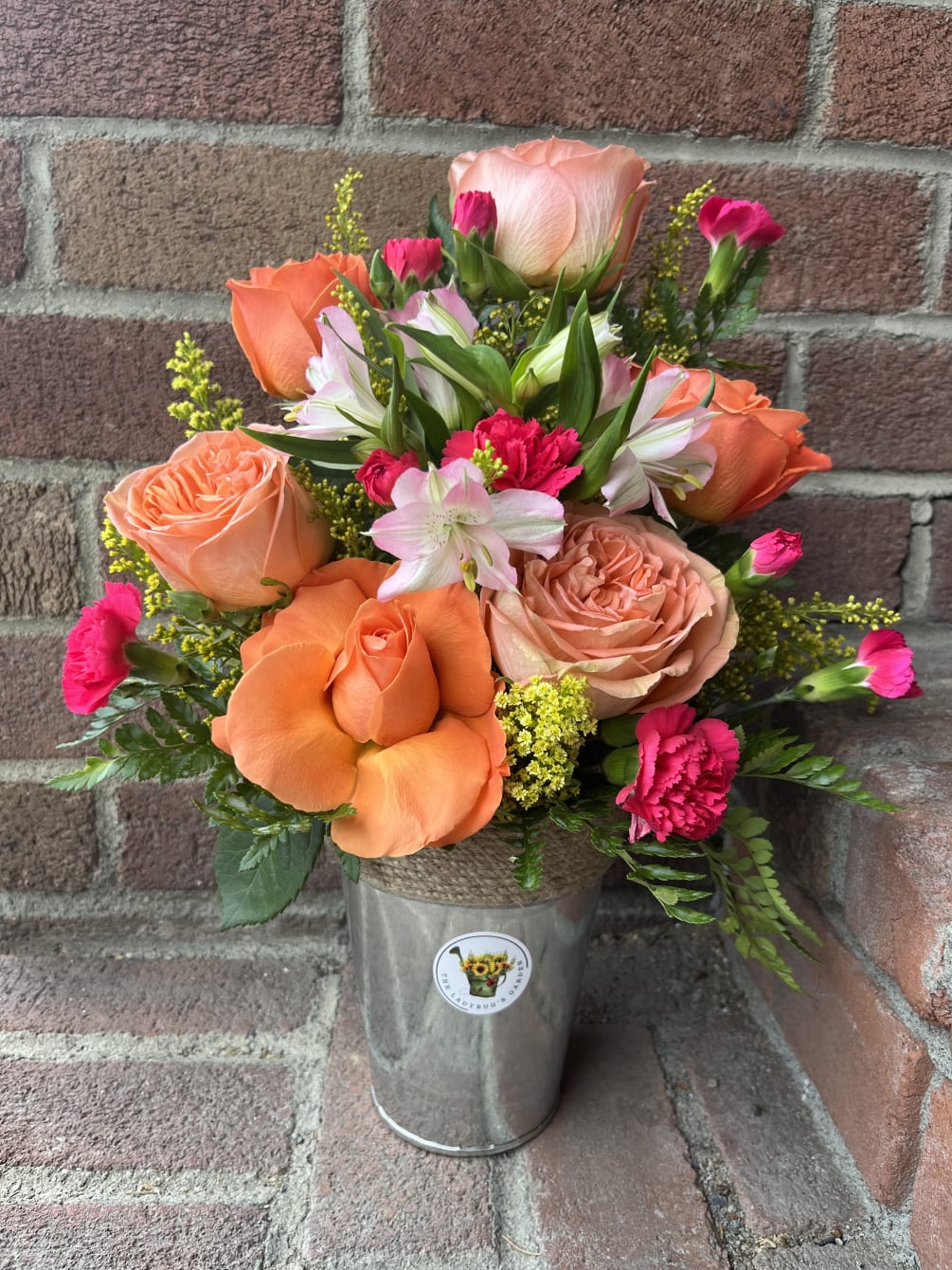 A beautiful bright designers choice arrangement of Roses and other seasonal flowers