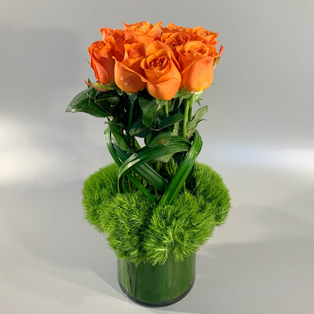 An modern gathering of orange roses, finished with sculpted grass and green