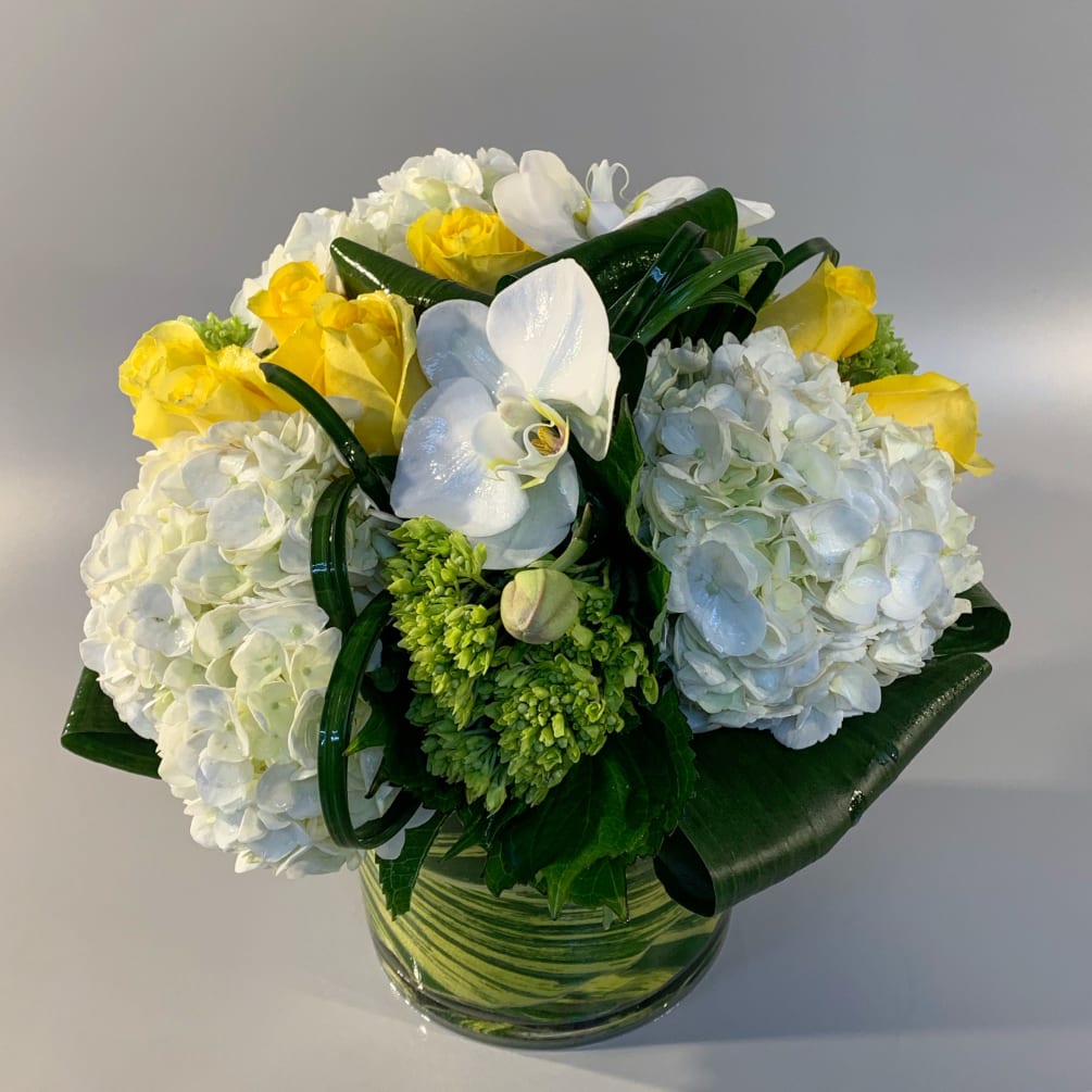 Hand-tied arrangement of vibrant roses, sculptural greenery, green hydrangea, and an orchid