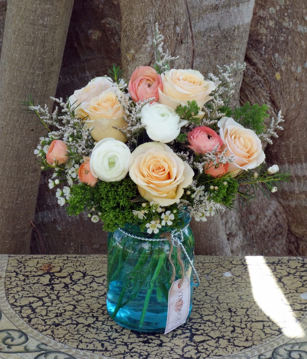 Beautiful blue jar filled with spring green trick, peach roses, peach and