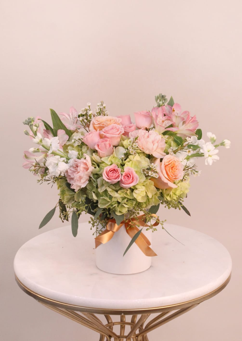 A romantic arrangement of peach, pink and  green flowers in a