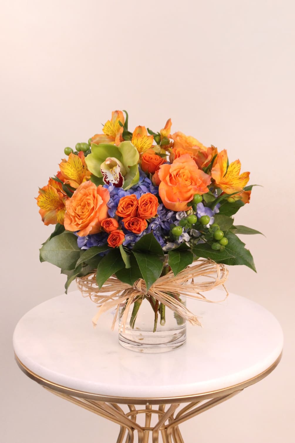 A bright and cheerful arrangement of hydrangeas, roses, orchid, alstromeria, and coffee