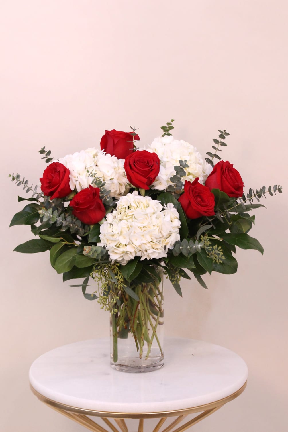 Half dozen of red roses with hydrangeas and mixed foliage arranged in