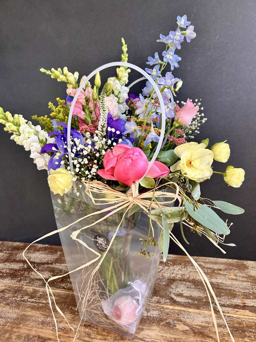A tote bag with an assortment of fresh blooms in a vase