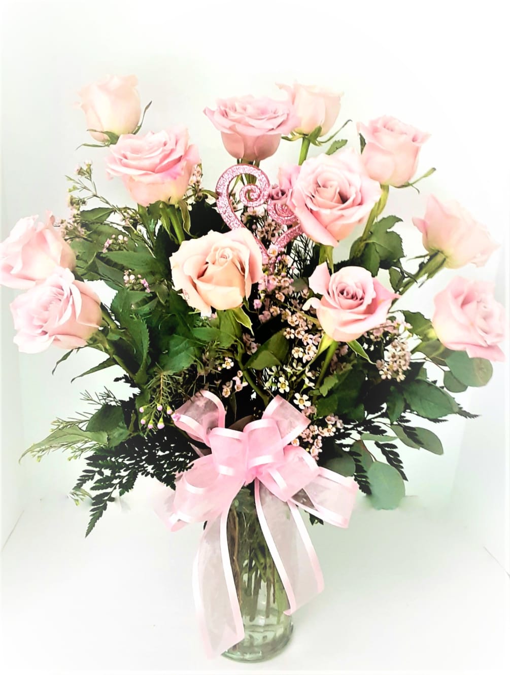 12 pink premium roses with fillers and greenery in a clear vase