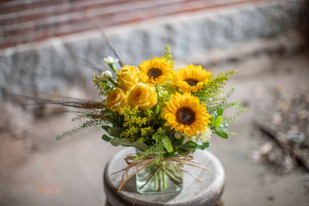 Sunflowers and yellow roses arranged in a compact fashion in a cube