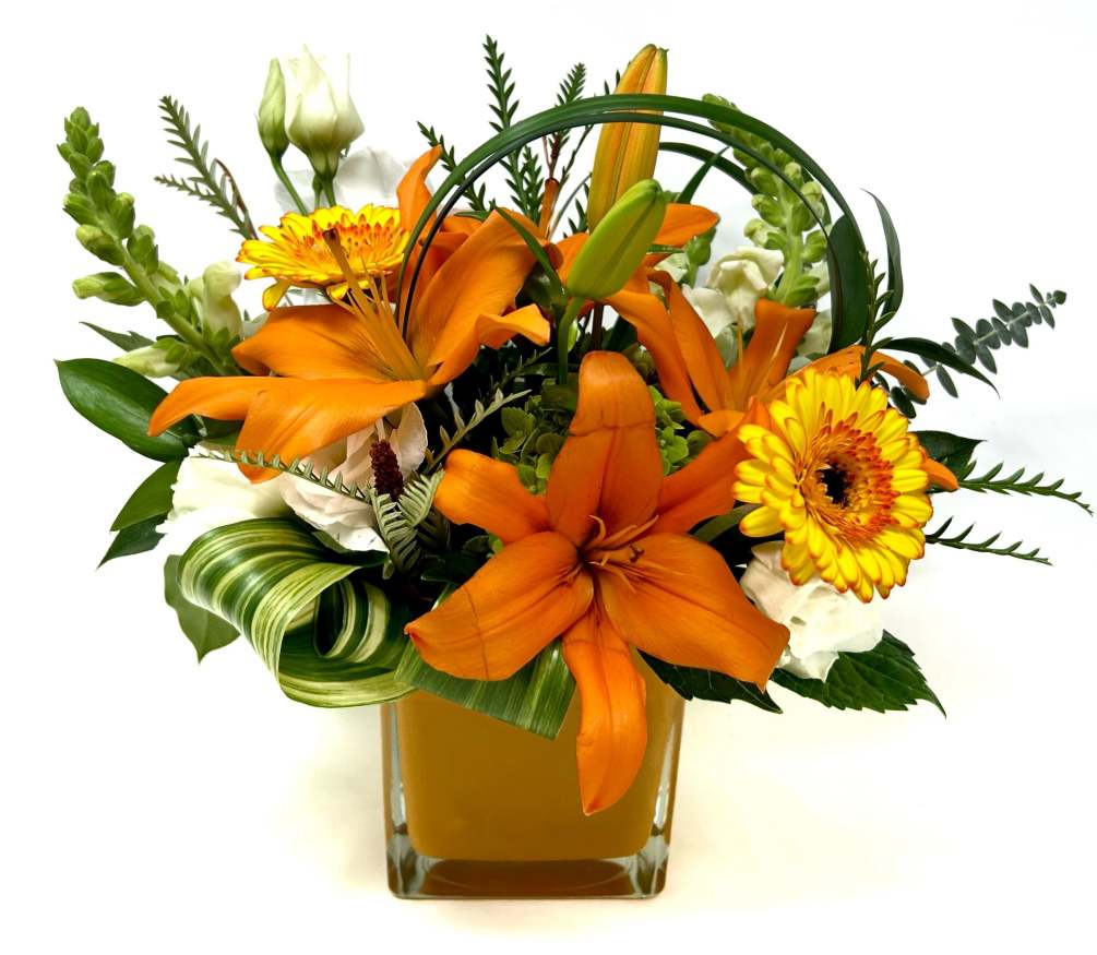 Bright orange asiatic lilies and other season blooms in a orange glass