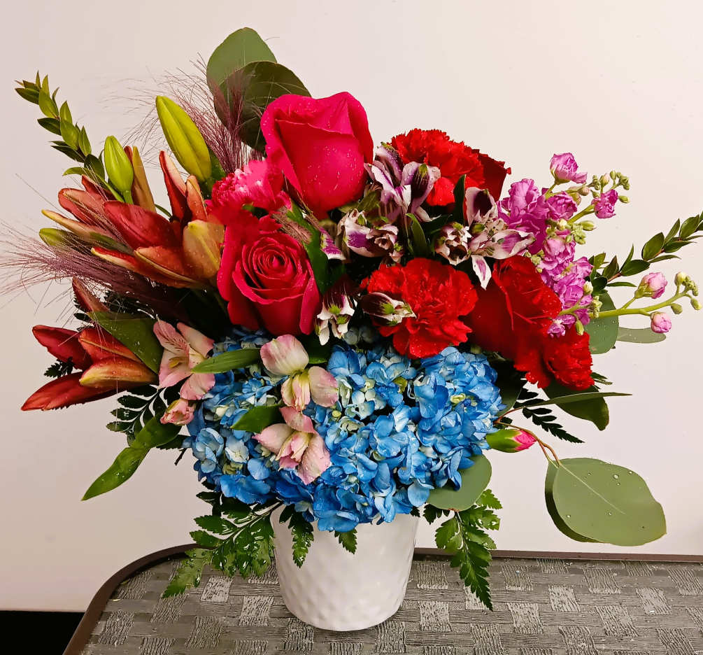 Fresh floral arrangement with roses, lilies, stock or snapdragons, greens, hydrangea, and
