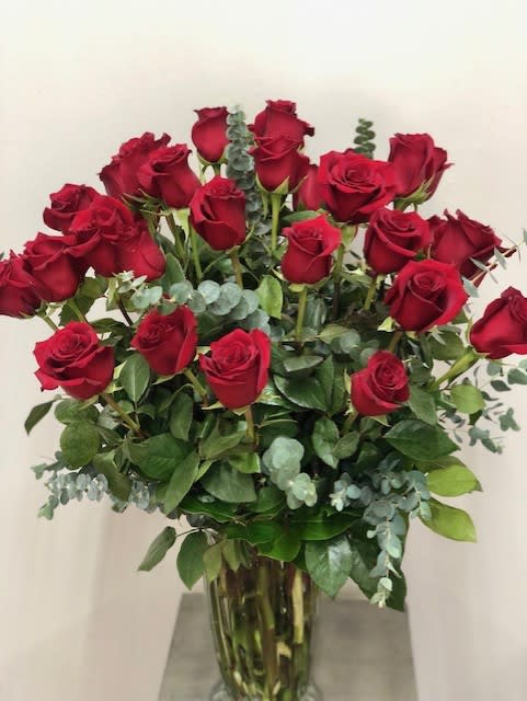 Three dozen roses arranged in a vase with gorgeous greenery will surely
