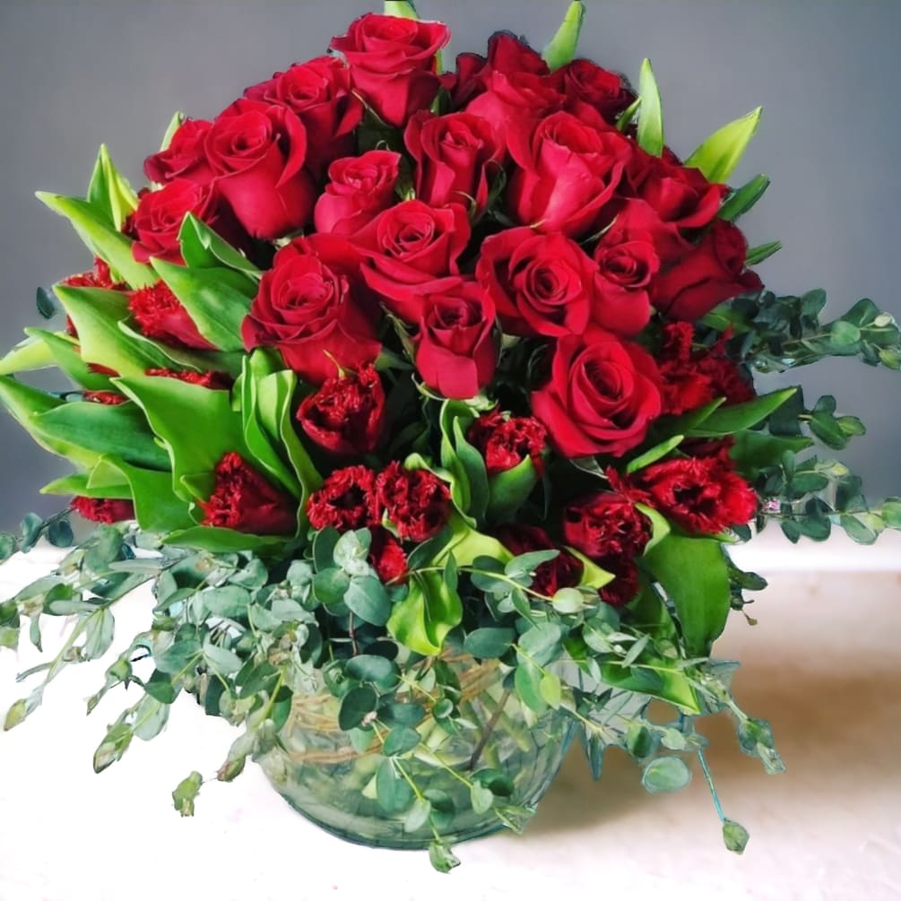 24 Red Roses Nestled in Red Tulips and foliage.  If red