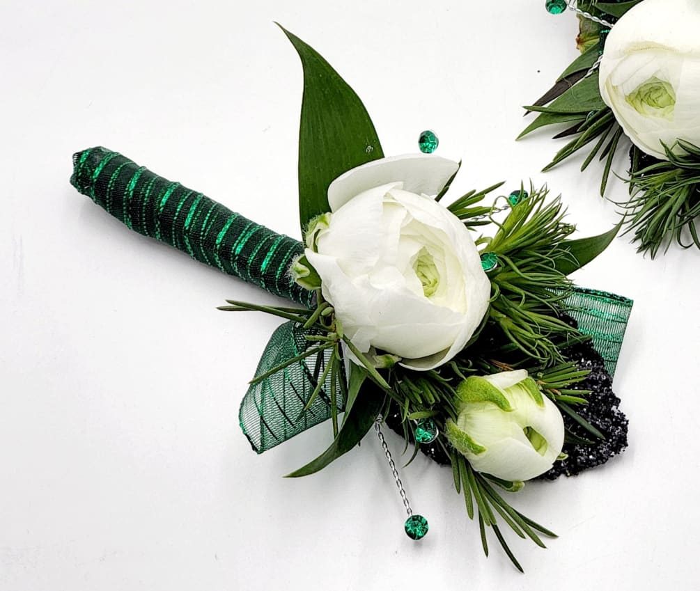 A boutonniere of white ranunculus, succulents, green ribbon and a black keepsake