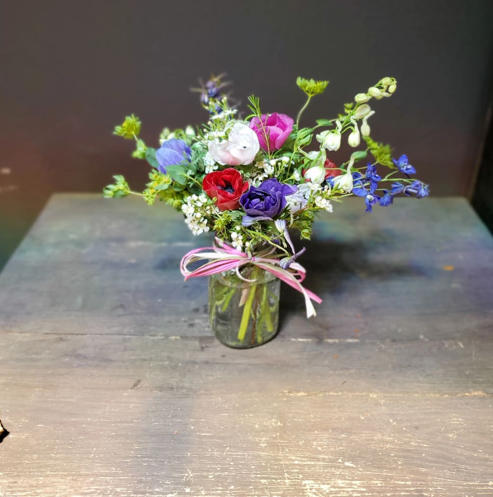 Cute, pretty wild flowers and Anemone in a small mason jar container.