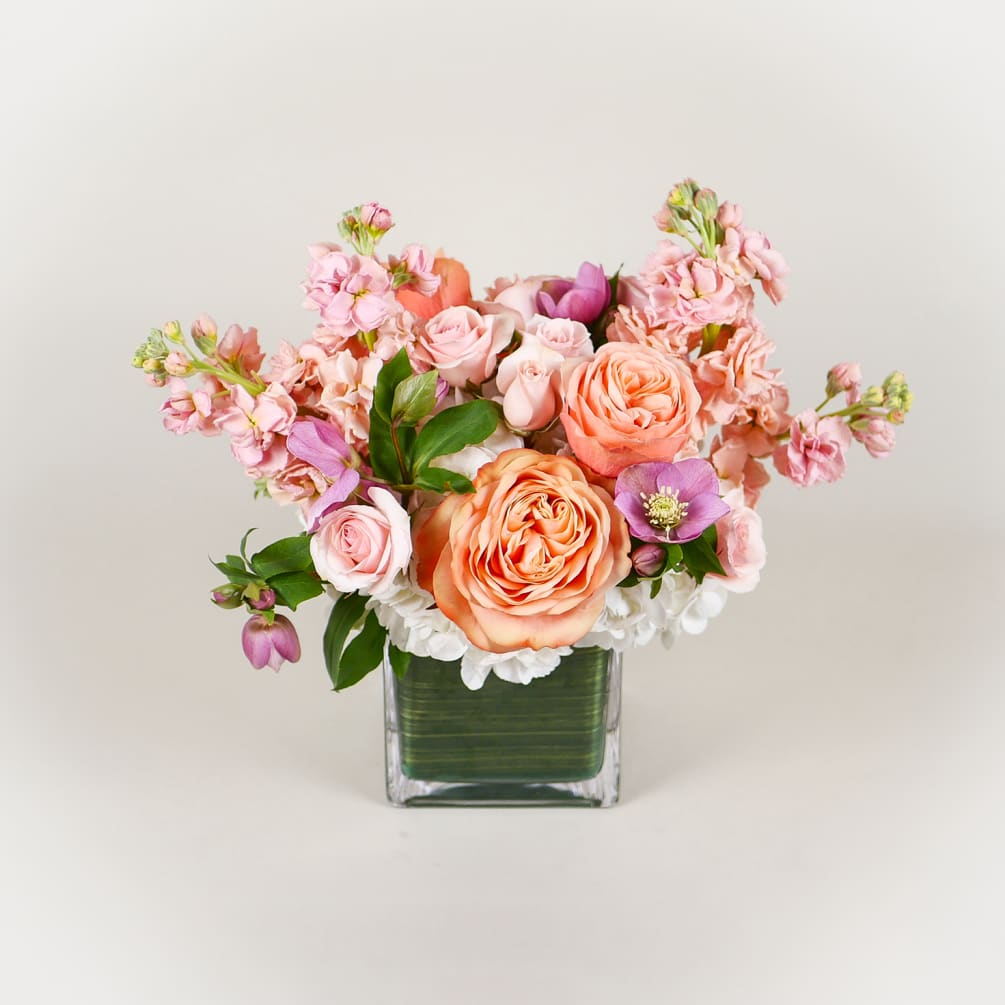 This bright arrangement boasts white hydrangeas, peach roses, fragrant peach stock, and