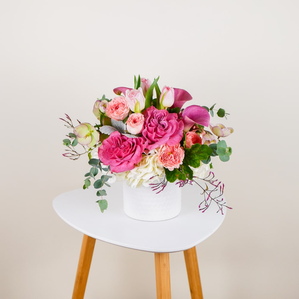 This petite arrangement features a harmonious blend of magenta and peach blooms