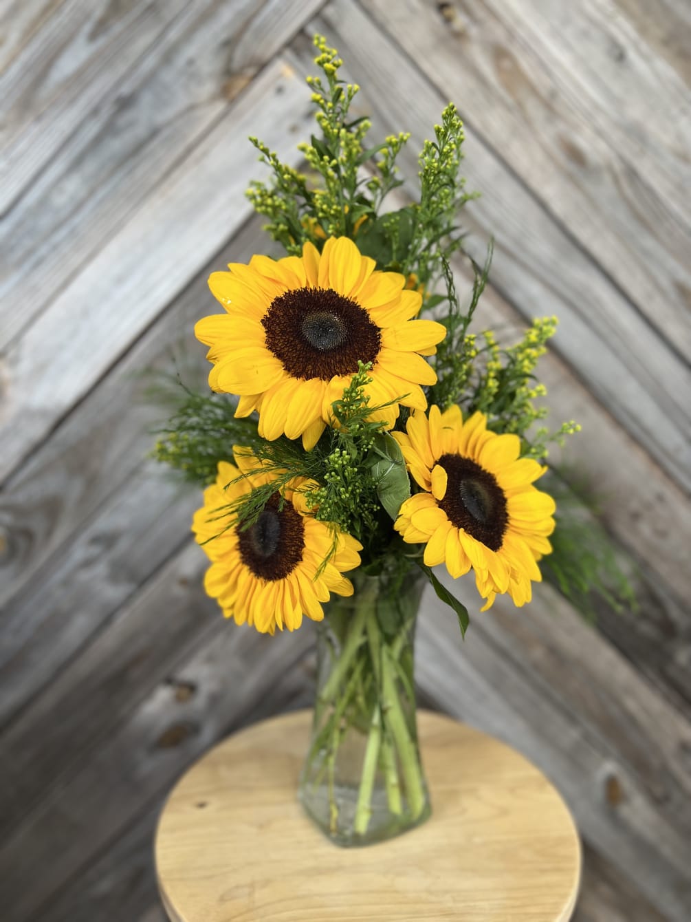 A captivating flower arrangement with large sunflowers and tree fern in a