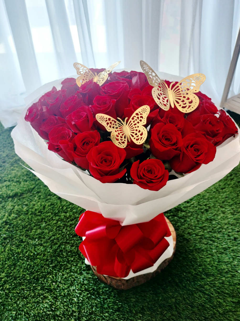 36 red roses wrapped in white paper with a red bow and