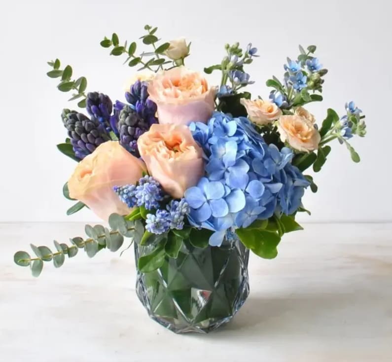 Peachy roses meets blue! This sweet arrangement is the perfect gift featuring