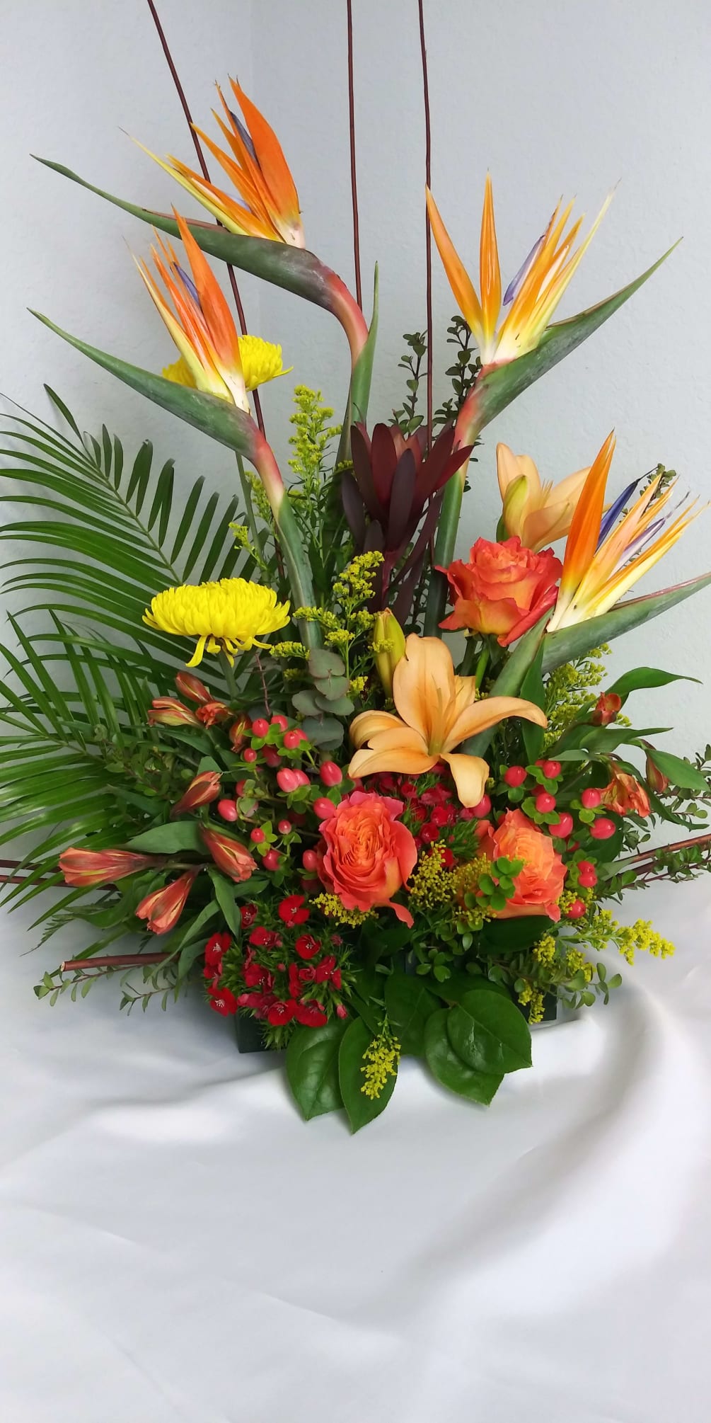 Tropical arrangement in oranges, yellows and reds with bird of paradise, orange
