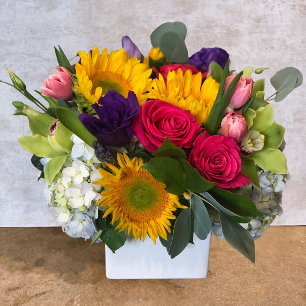 A stunning bouquet bursting with sunflowers, roses, and tulips in a rich
