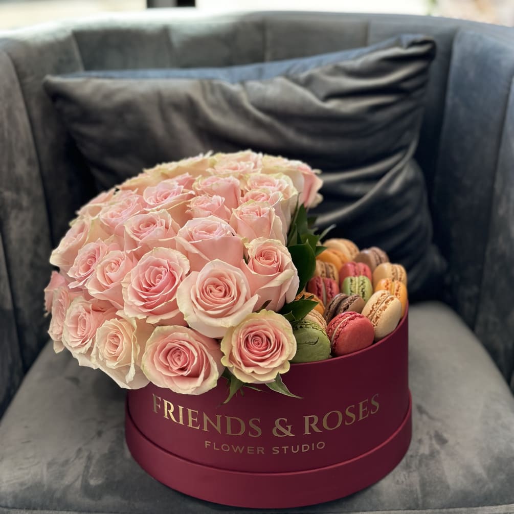 A sweet box filled with macarons and light pink roses is not