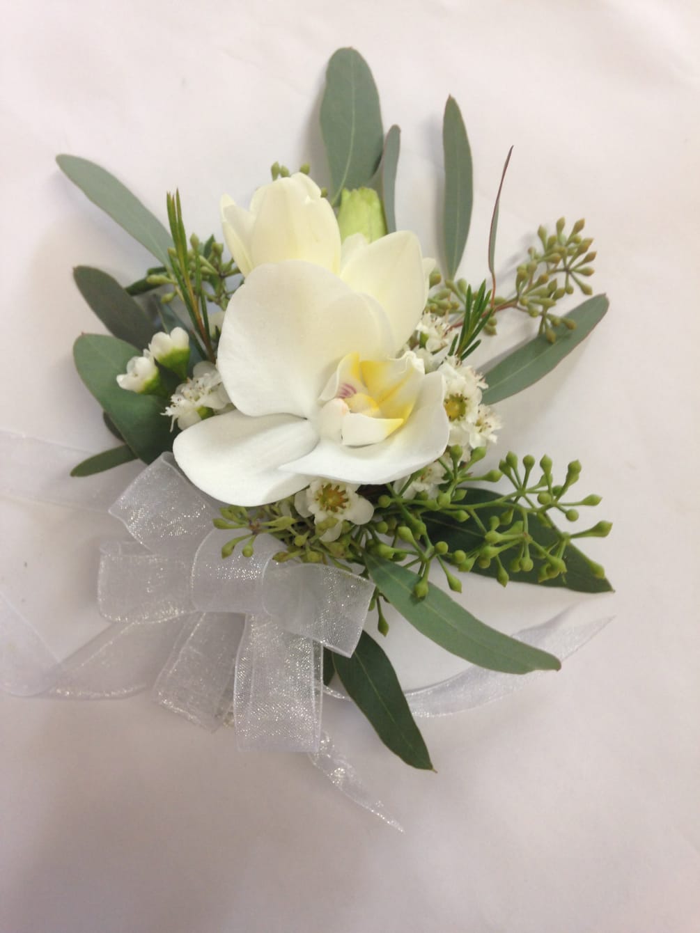 A regal corsage of white phaelenopsis orchid and seasonal greens.