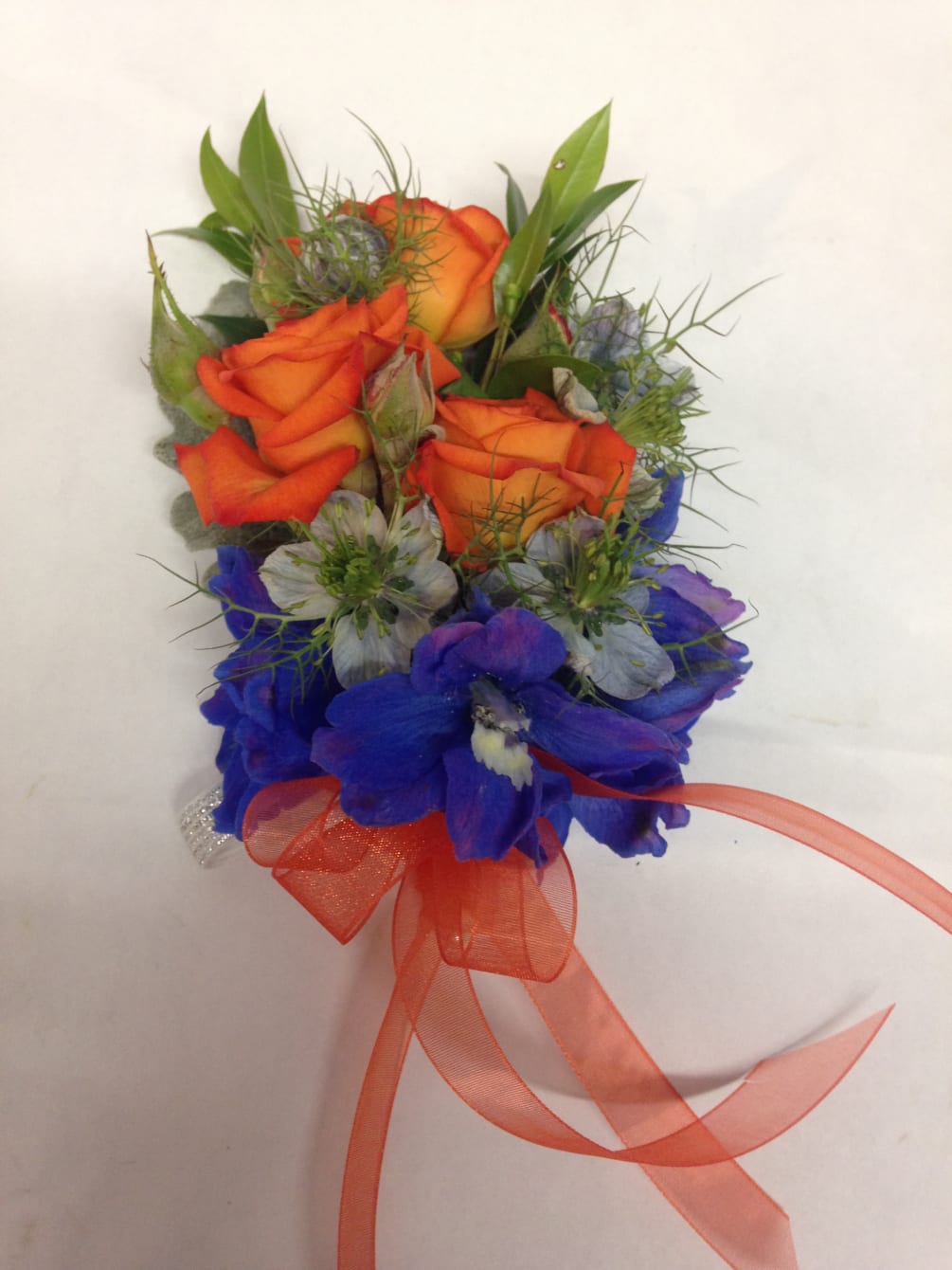 A bold, contrasting orange and blue wrist corsage for prom or a