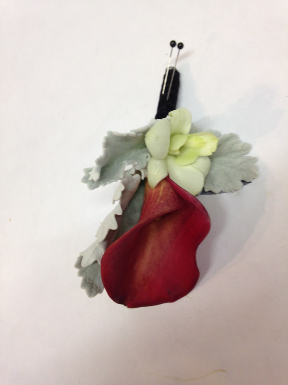 A burgundy calla is accented by dusty miller and a simple orchid