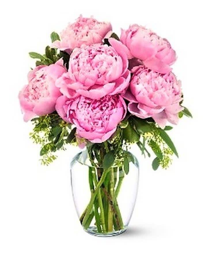 Pink peonies arranged in a clear glass vase accented with greens.