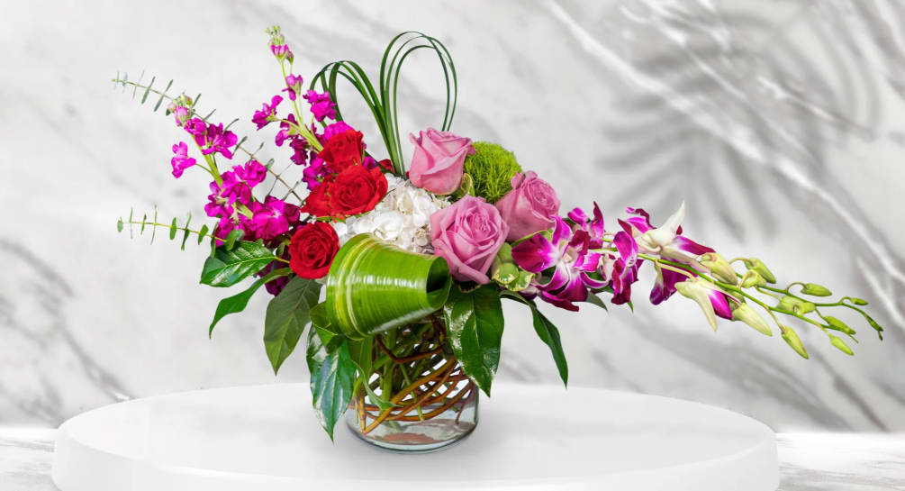 This unique design includes purple dendrobium orchids, purple roses, red spray roses