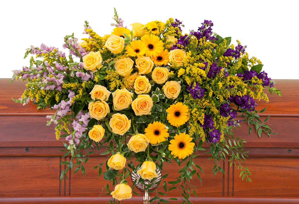 Bright, vivid yellow and purple flowers create a memorable casket spray.