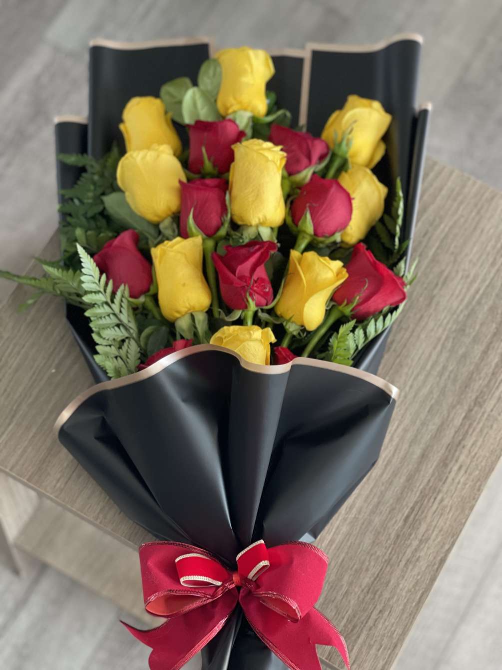 Brightful bouquet of 18 long stem red and yellow roses, leather leaves
