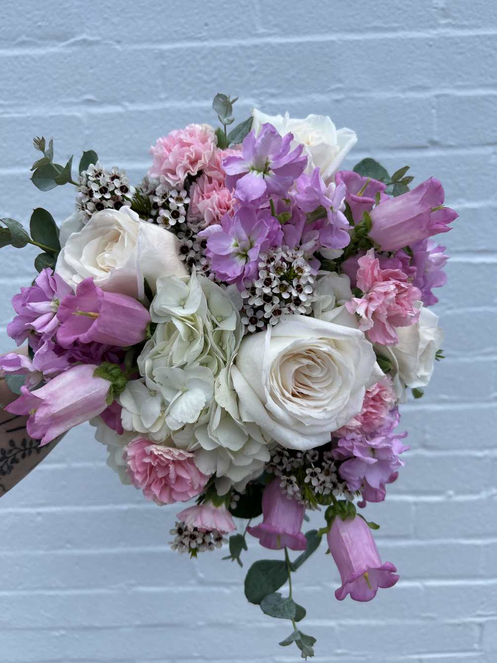 A designer&#039;s choice bouquet of light pink and white seasonal flowers will